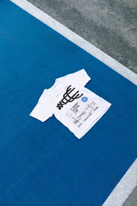 White t-shirt lying on textured blue background with gray concrete border