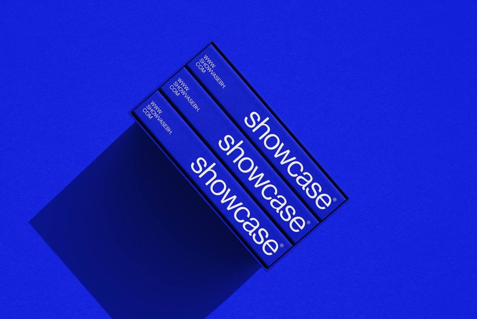 Three blue book spines in black box on vibrant blue background tilted
