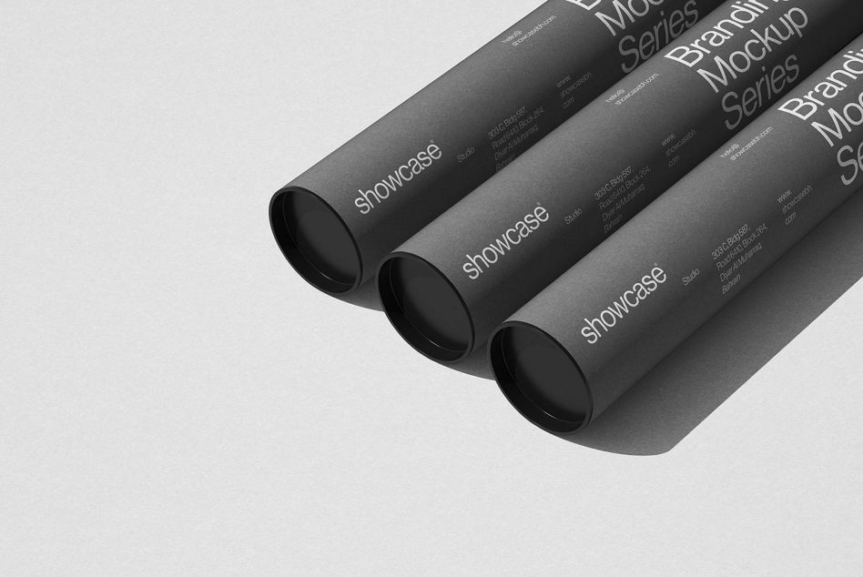 Three rolled dark gray branded tubes with text on neutral background
