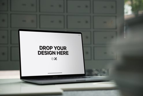 Laptop mockup on desk with editable screen for design presentation, modern workspace setting, ideal for showcasing web and app designs.