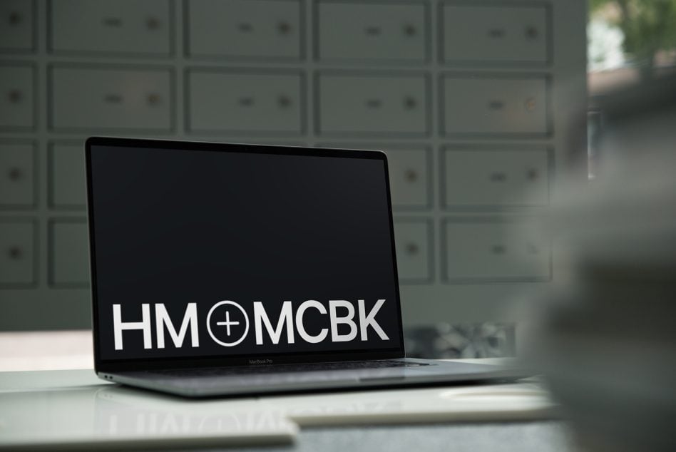 MacBook Pro laptop displaying logo on dark screen in office setting