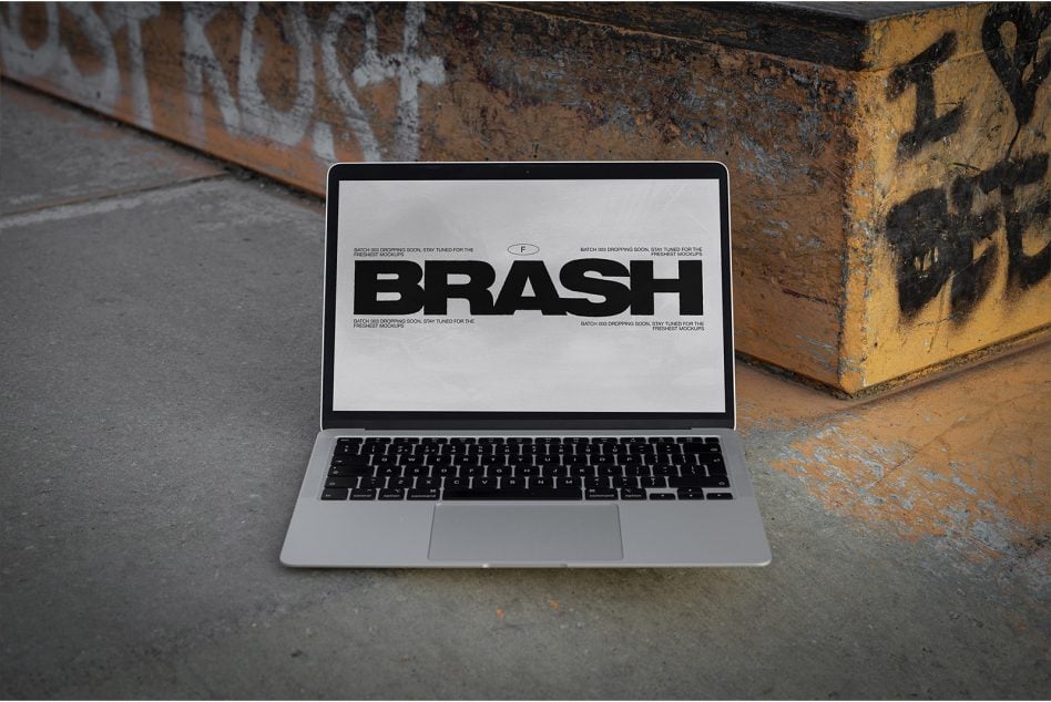 MacBook on street showing BRASH typography mockup on light screen
