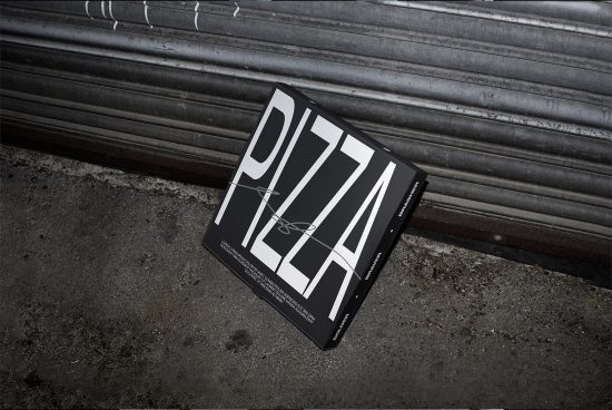 Pizza box packaging mockup with bold typography design on a gritty urban background, ideal for showcasing branding and packaging designs.