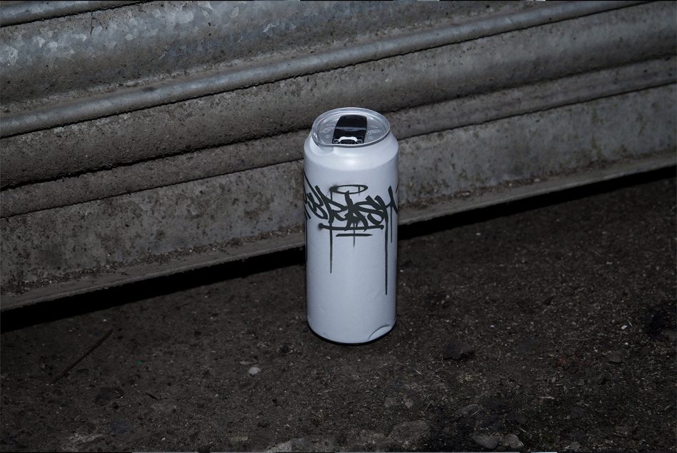 White paint can featuring bold black graffiti lettering on concrete stairs