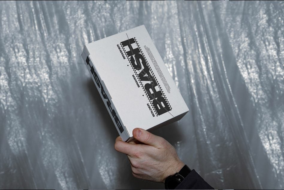 Hand holding white box with black dotted pattern title treatment