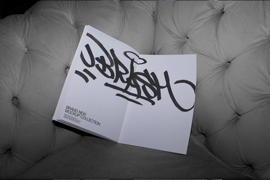 Open magazine mockup on a gray couch featuring bold graffiti-style font, ideal for graphic design and font presentation.