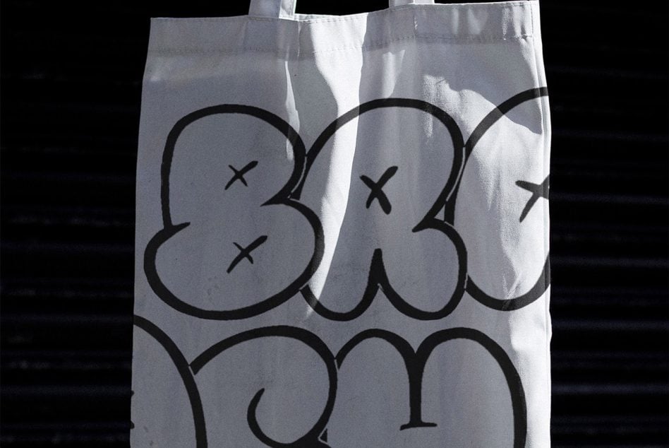 Tote bag mockup displaying thick outlined typography with playful character elements