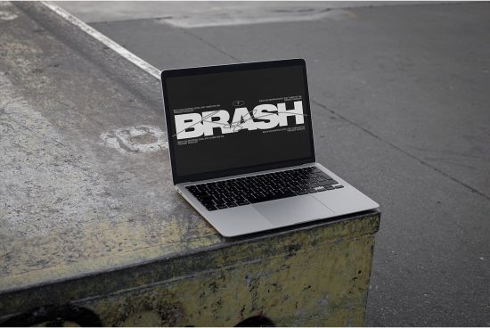 Laptop on urban concrete displaying bold font design, ideal for graphic designers looking for typography inspiration in mockup setting.