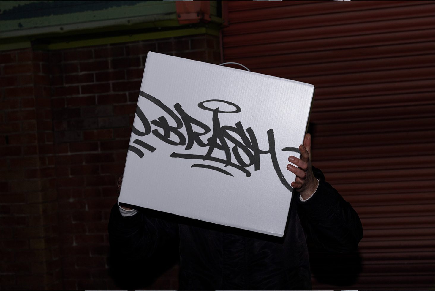 Person holding canvas with black graffiti art, urban style, perfect for mockup designs and modern templates for designers.