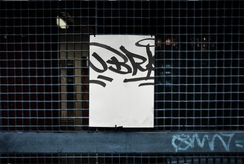 Urban poster mockup with graffiti style font, displayed on metal grid for contemporary graphic design projects.