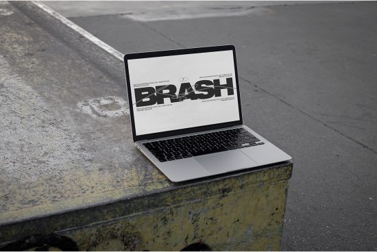 Laptop on concrete ledge showcasing bold BRASH font design, ideal for designers looking for mockups and typography inspiration.