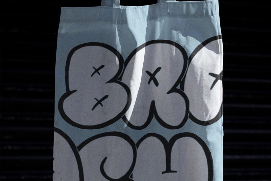 Close-up of tote front showing chunky bubble letter design with x eyes detail