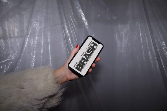Woman holding smartphone with bold brush font display, fur coat detail, against a plastic sheet backdrop, for mockup graphic design.