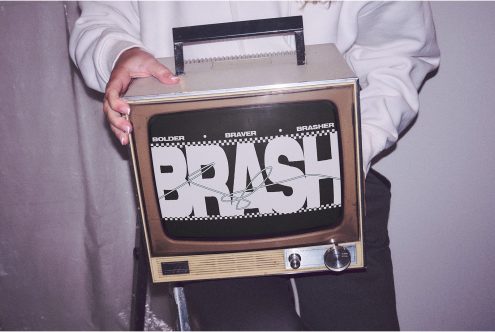 Person holding a vintage TV displaying bold graphic font, ideal for retro mockups, graphic design, and font showcases. Vintage aesthetic design element.