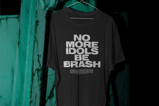 Black t-shirt with bold typography design hanging on a green rustic background, perfect for graphic design and mockup categories.