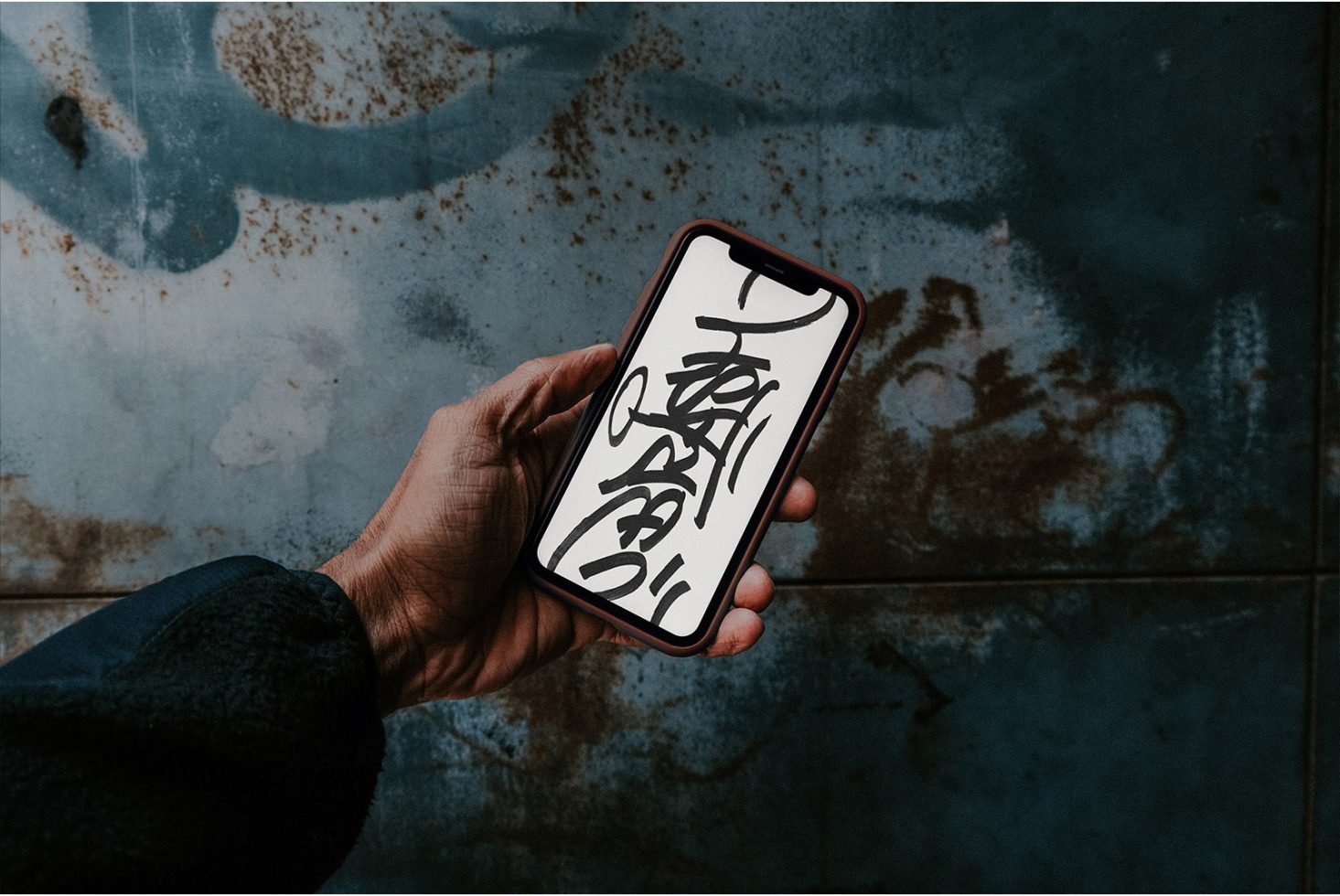 Hand holding smartphone with calligraphy art on screen for graphics template mockup, urban grunge background, design asset.