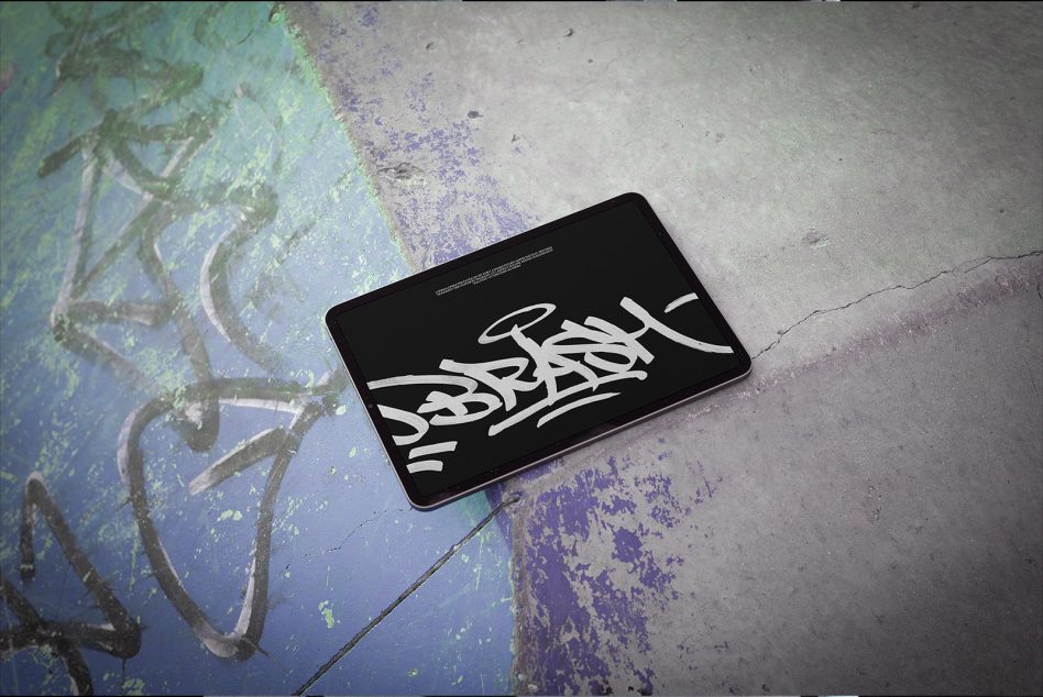 Tablet on distressed colorful pavement displaying wildstyle graffiti letters