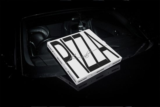 Mockup of bold pizza box packaging design with black and white contrast atop a car dashboard, ideal for showcasing branding projects.