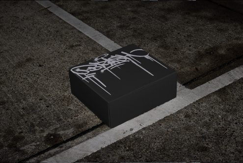 Realistic shoe box mockup with graffiti design on urban street asphalt for packaging presentation, ideal for designers looking for city-themed templates.