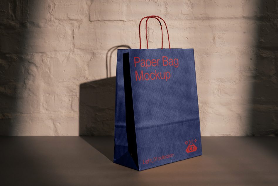 Navy paper bag with red handles sitting on table with brick background