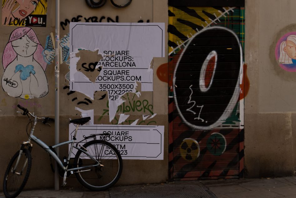 Torn white square poster on weathered wall next to graffiti bike leaning