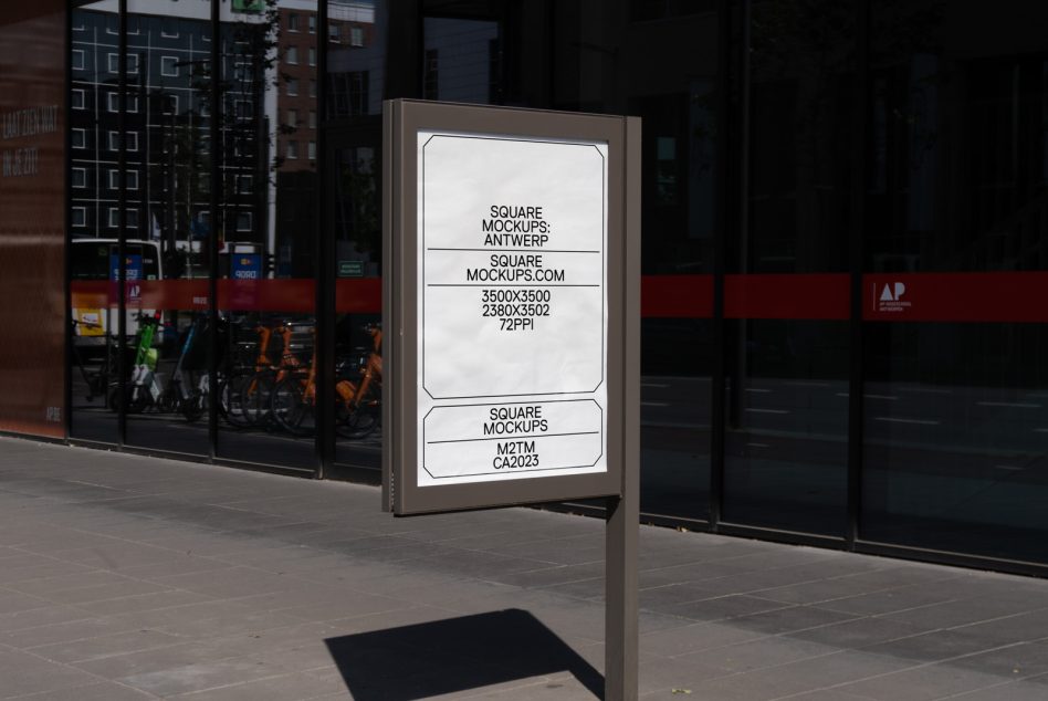Street-level lightbox sign on tan pole outside storefront, white screen mockup
