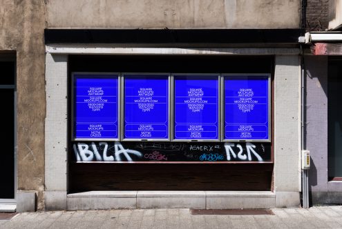 Four glowing blue neon square posters across storefront, vibrant against weathered facade