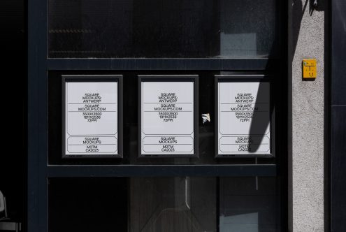Three white square mockups in storefront window with black frame, harsh sunlight shadows