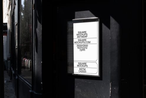 Illuminated window display on dark storefront showing white mockup layout at night
