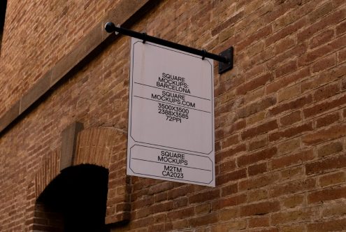 White square sign hanging on brick wall with black metal bracket in Barcelona