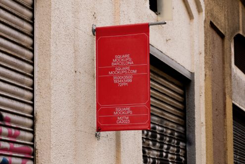 Red square hanging banner on weathered brick wall between metal shutters