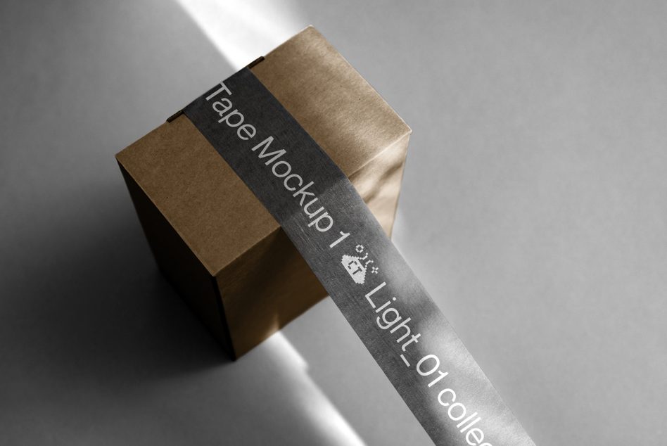 Kraft colored box with dark gray band wrapping around it on white surface