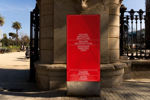 Red rectangular poster mounted on stone column in Barcelona park