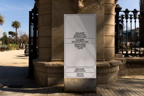 White rectangular poster mounted on stone column in Barcelona park