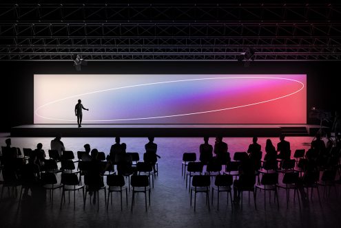 Silhouette of a speaker on stage with colorful gradient background, audience in foreground, for presentation templates or mockup design.