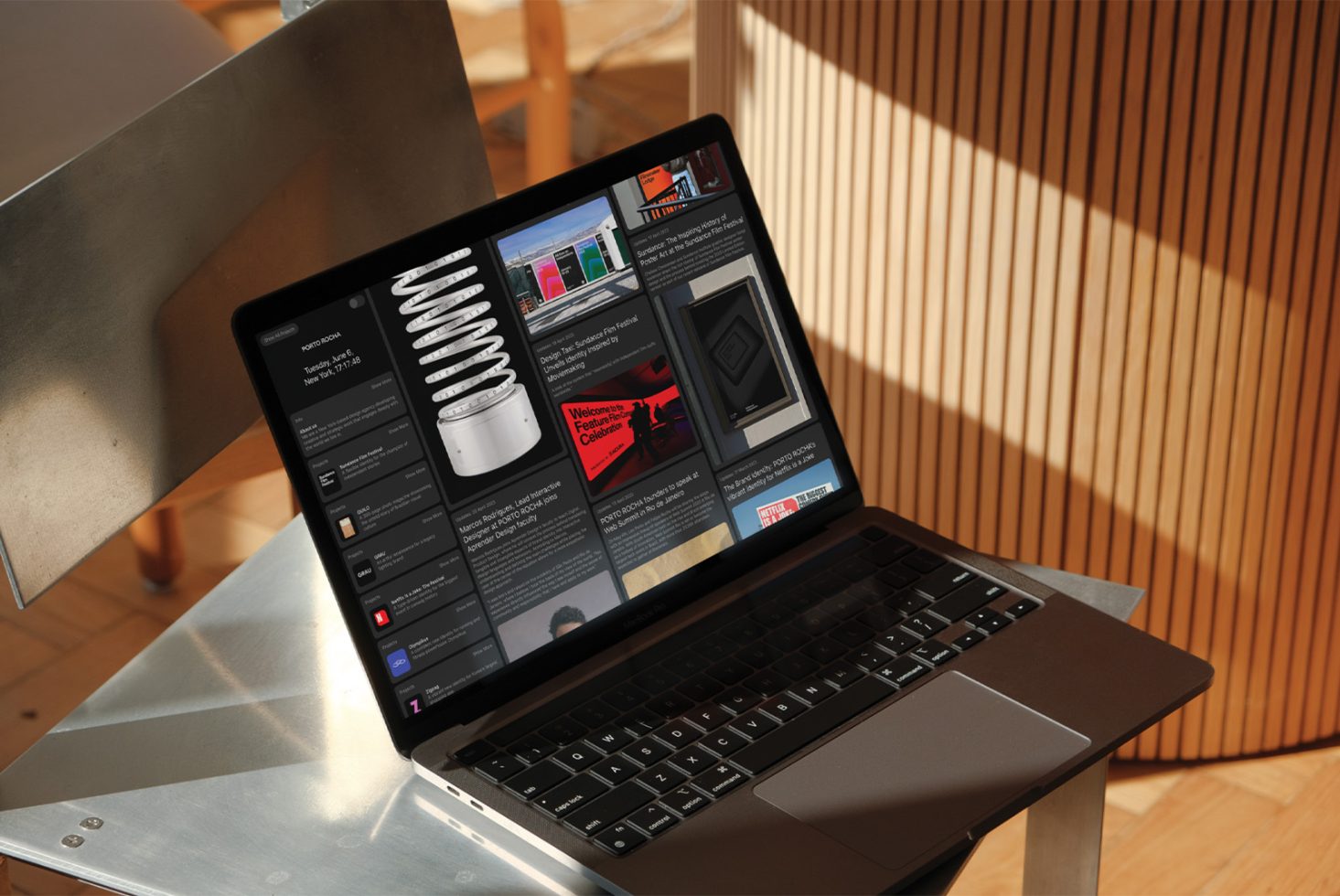 Laptop on desk displaying graphic design software interface, sunlight casting shadows, modern creative workspace, digital mockup presentation.