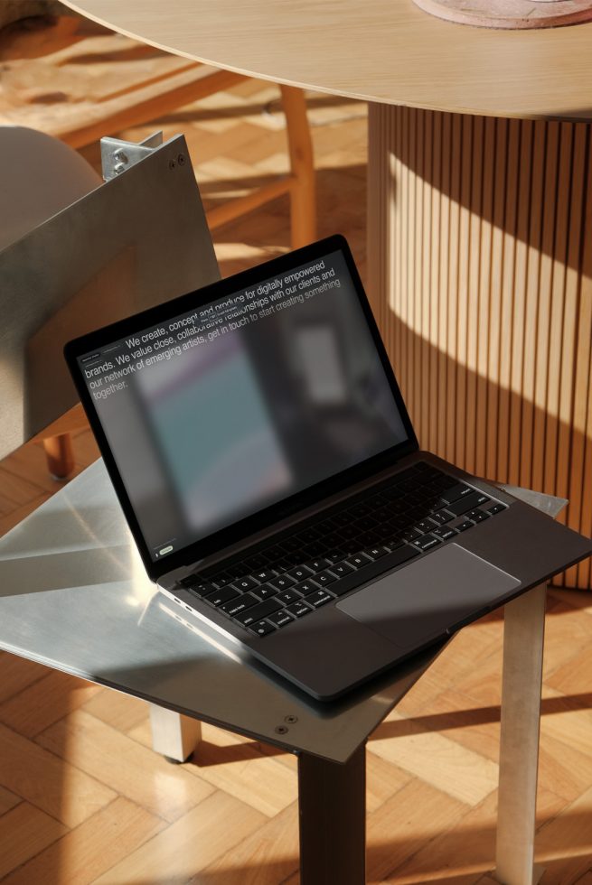 Laptop with blurred screen on a modern metal stand in a sunny room, ideal for mockup graphics, showcasing digital design work.