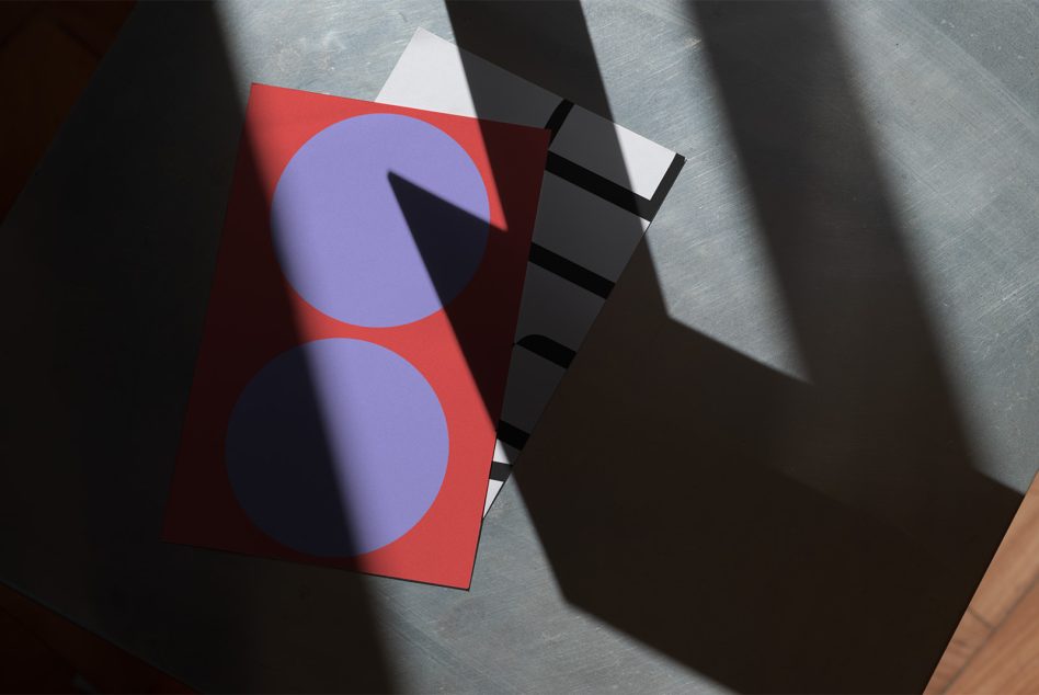 Red card with purple circles, black striped shapes, stacked alongside black cards in sunlight