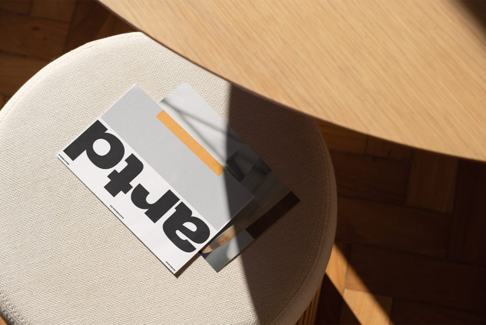 Magazine mockup on cream chair with black bold typography below orange accent stripe