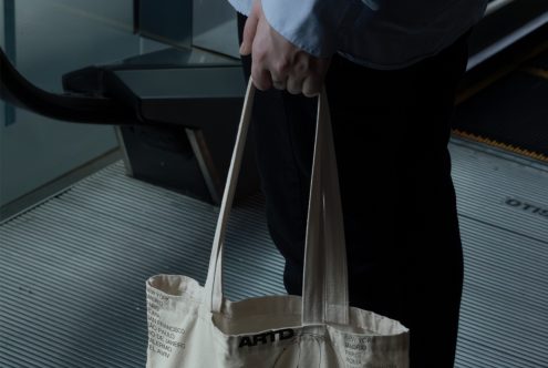 Close up of person carrying light colored tote bag with minimalist line drawings