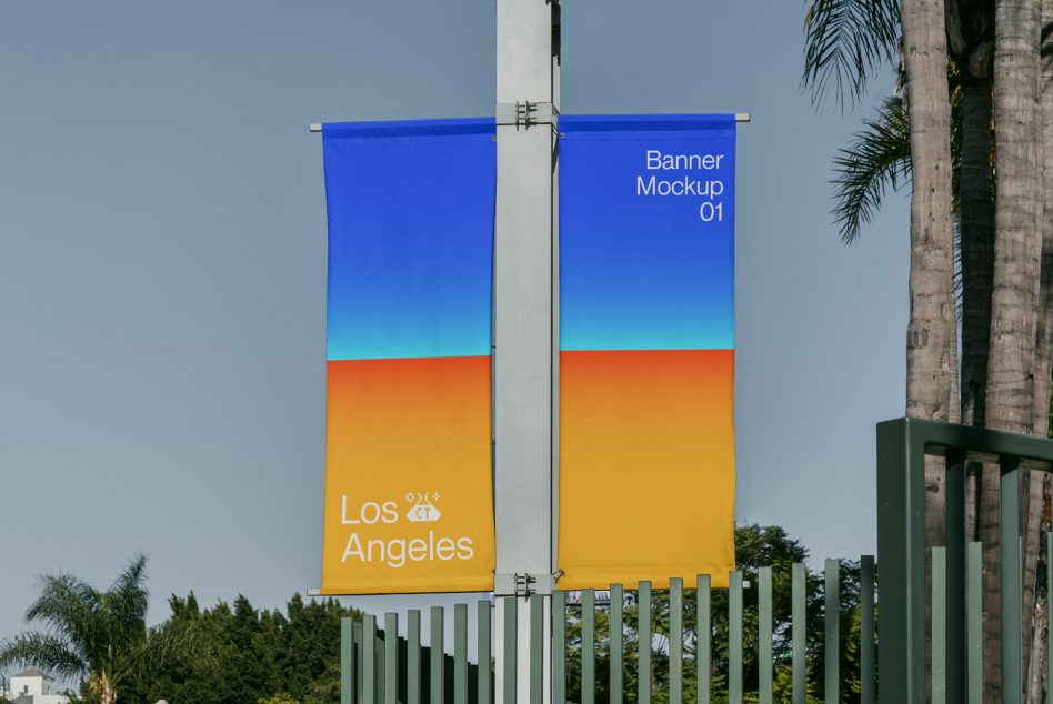 Twin fabric banners with blue orange gradient design hanging from pole in outdoor setting