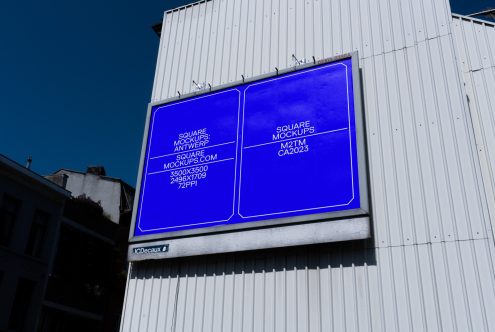 Glowing neon blue billboard on industrial metal facade displaying square mockup layouts