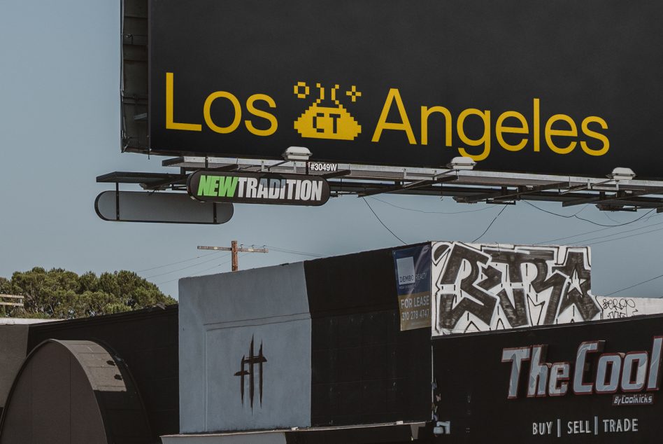 Large yellow Los Angeles sign on black highway billboard above street stores
