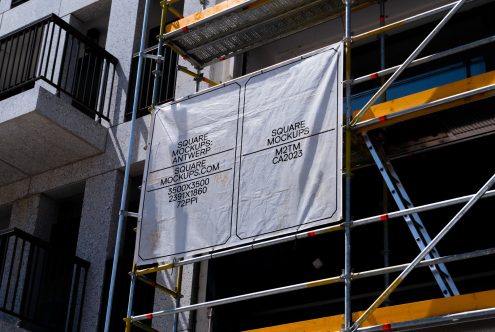 White fabric banner mockup hanging on construction scaffolding frame