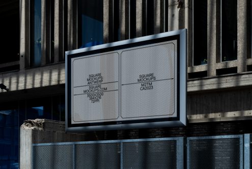 Outdoor billboard with two white panels on industrial building facade showing mockup layout