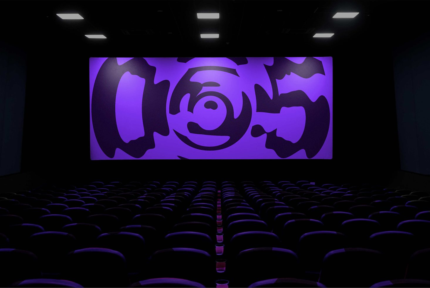 Cinema hall with empty seats and a large display showcasing abstract purple graphic design, ideal for mockup presentations.