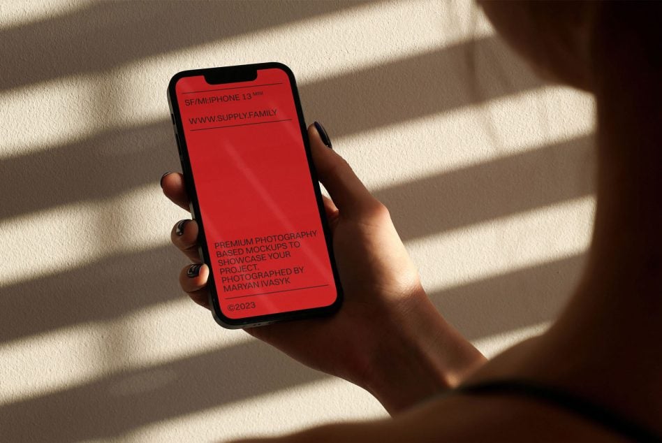 iPhone 13 Mini mockup displaying red screen held in hand with strong sunlight
