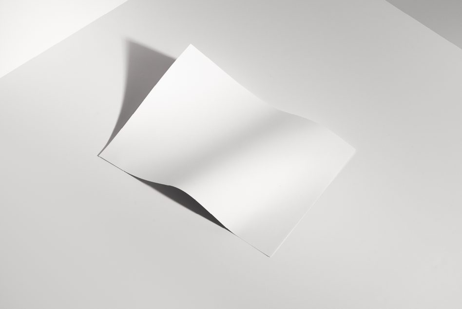 Blank folded paper mockup on gray surface with soft shadows