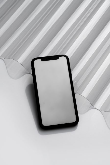 Black phone mockup with blank white screen on striped gray background