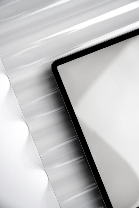 Close up of tablet edge with black border, plain white paper beside it